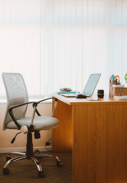 oficina con una silla gris y una mesa con un portatil